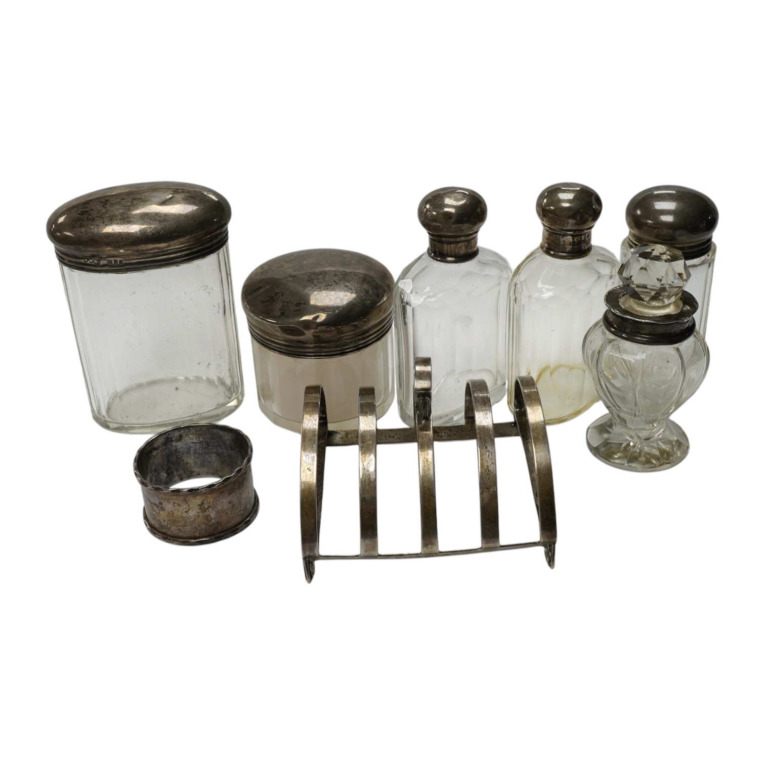 An Art Deco silver five bar toast rack by Charles S. Green & Co Ltd, Birmingham, 1935, 9cm, a silver napkin ring and six assorted silver topped glass toilet bottles. Condition - poor to fair